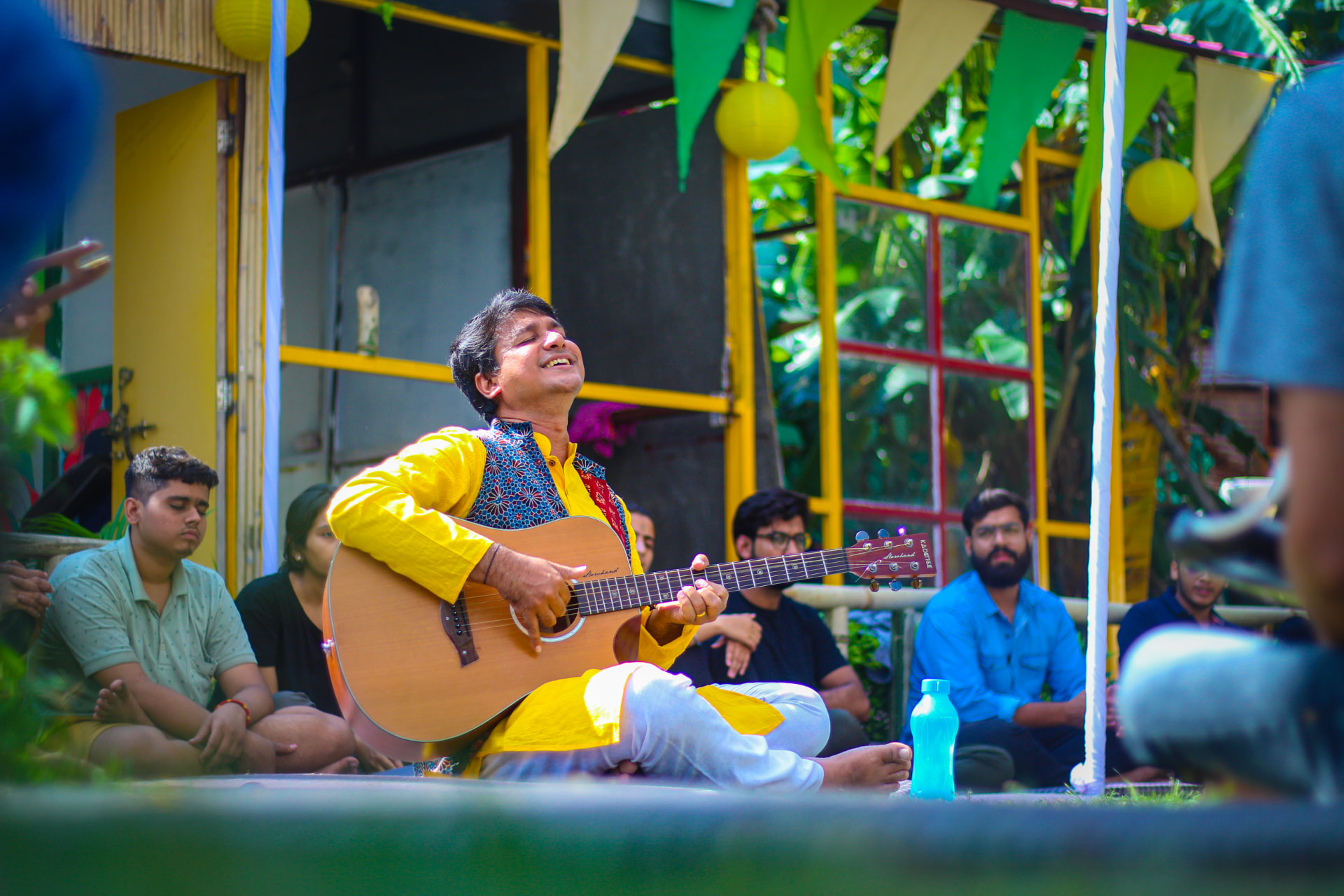 Vedanth Bharadwaj performing with a guitar for a seated audience